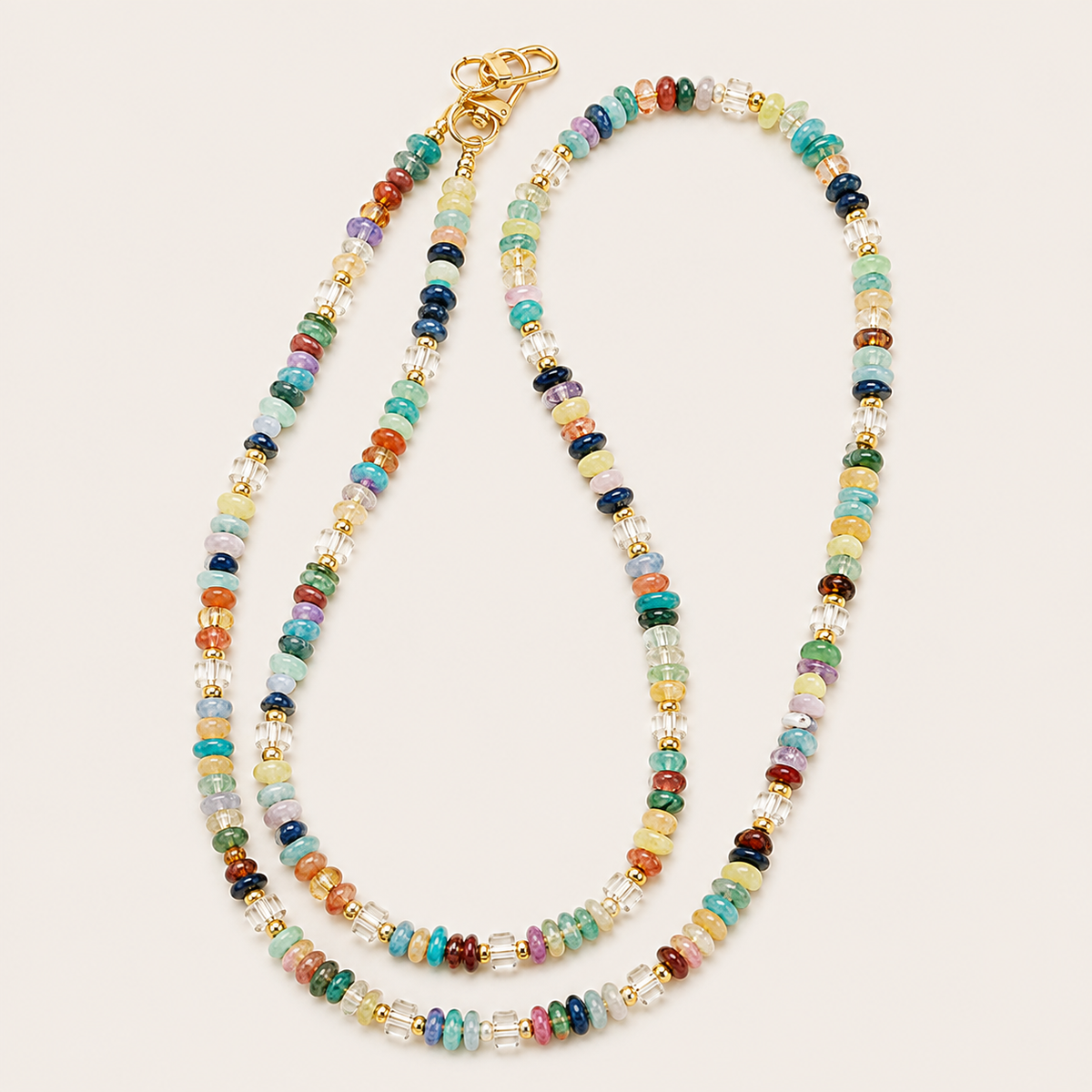 Multicolour rondelle bead phone chain with gold clasps laid flat on cream — Folie à Trois Hollis long phone chain