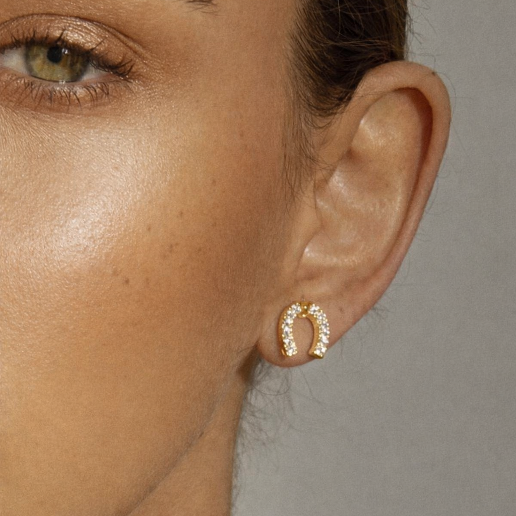 Worn on a model's ear, the Horseshoe EARRINGS add a small pave crystal horseshoe accent near the lobe.