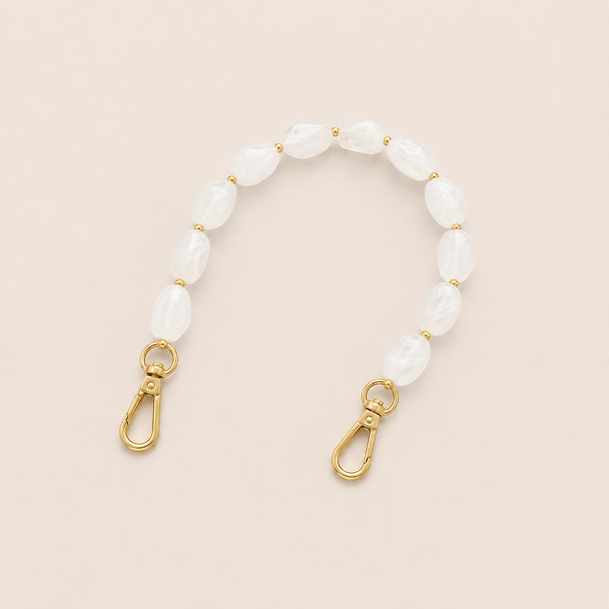 Folie à Trois Isolde short phone chain in frosted white opal-effect beads with gold accent beads and gold clasps, styled flat on a cream background.