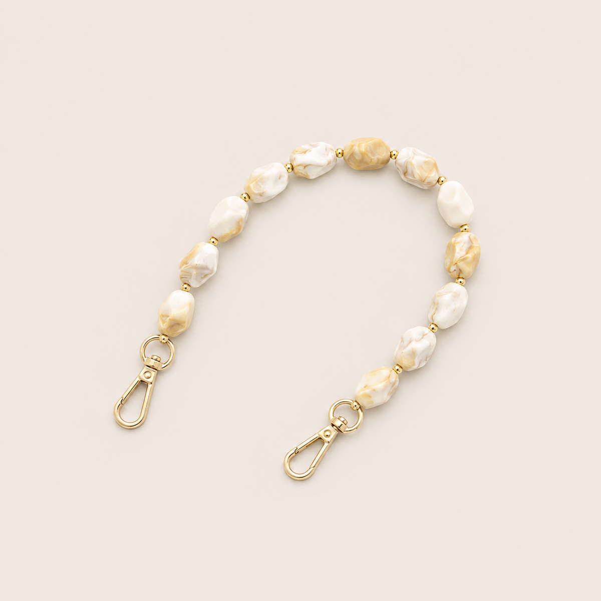Folie à Trois Isolde short phone chain in beige marbled beads with gold accent beads and gold lobster clasps, laid flat on a cream background.