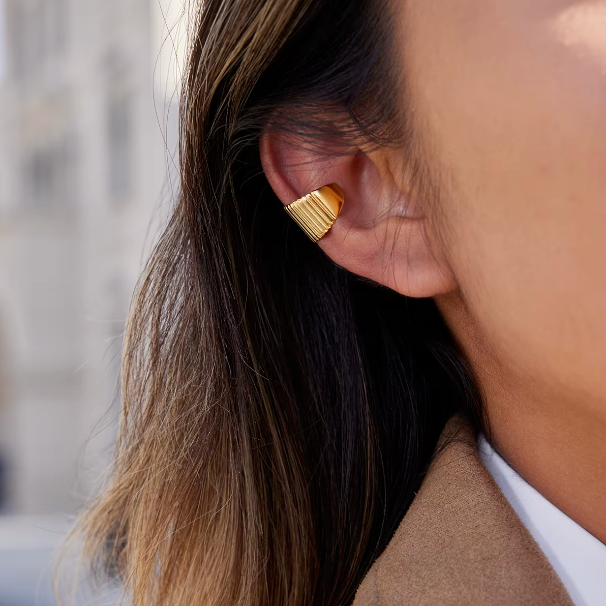 Close-up of a model wearing a gold Ivette EAR CUFF with a fluted, ribbed texture along her upper ear.