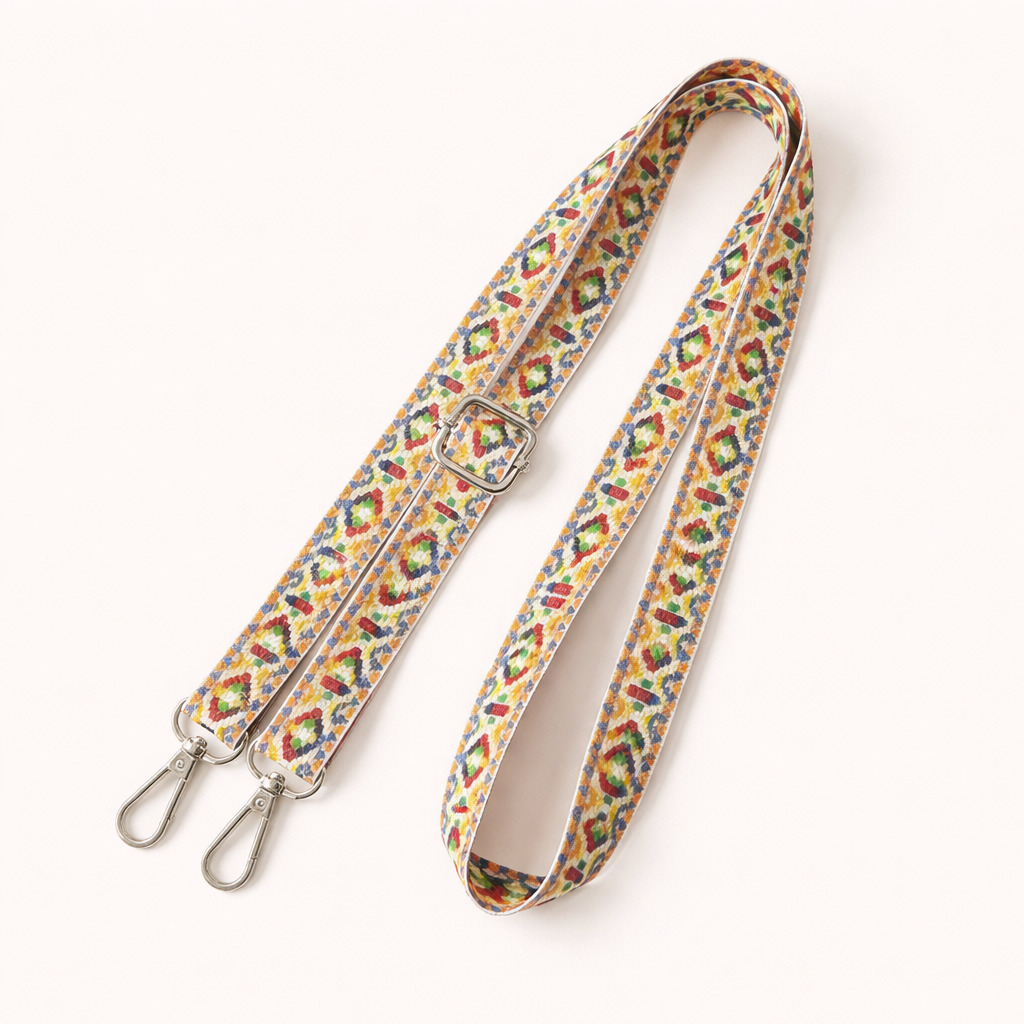 Woven Jetlag long phone strap in a multicolor yellow, red, and green print, coiled flat with silver clasps.