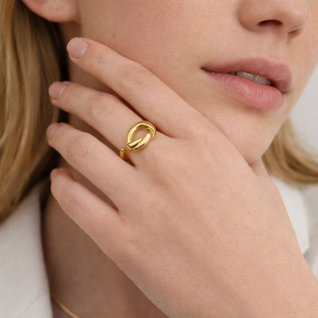 Close-up of a hand near the chin wearing the open gold Knotted RING, its sculpted knot catching the light.
