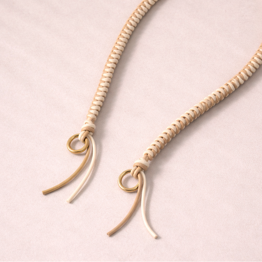 Cream braided Layover long phone strap, close-up of the knotted gold ring and fringe end.