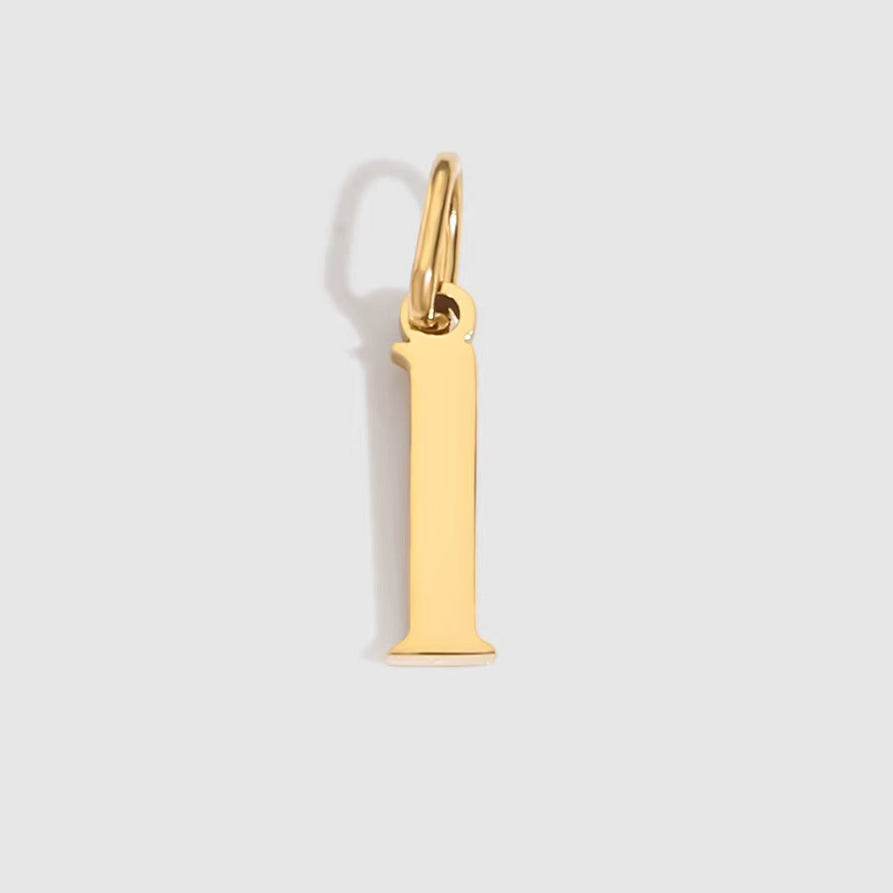 The Letter CHARM in lowercase l, a polished gold pendant in a serif l shape, shown in close-up on a light grey background.