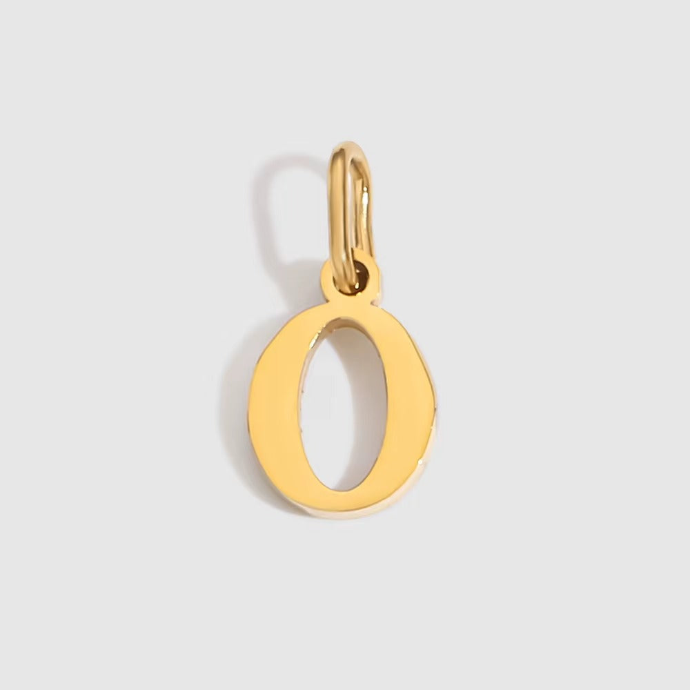 The Letter CHARM in lowercase o, a polished gold pendant in a serif o shape, shown in close-up on a light grey background.