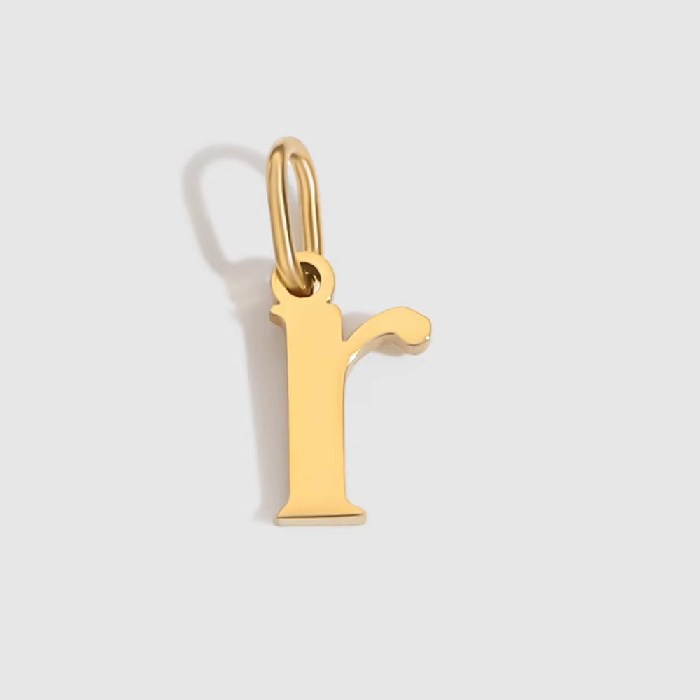 The Letter CHARM in lowercase r, a polished gold pendant in a serif r shape, shown in close-up on a light grey background.