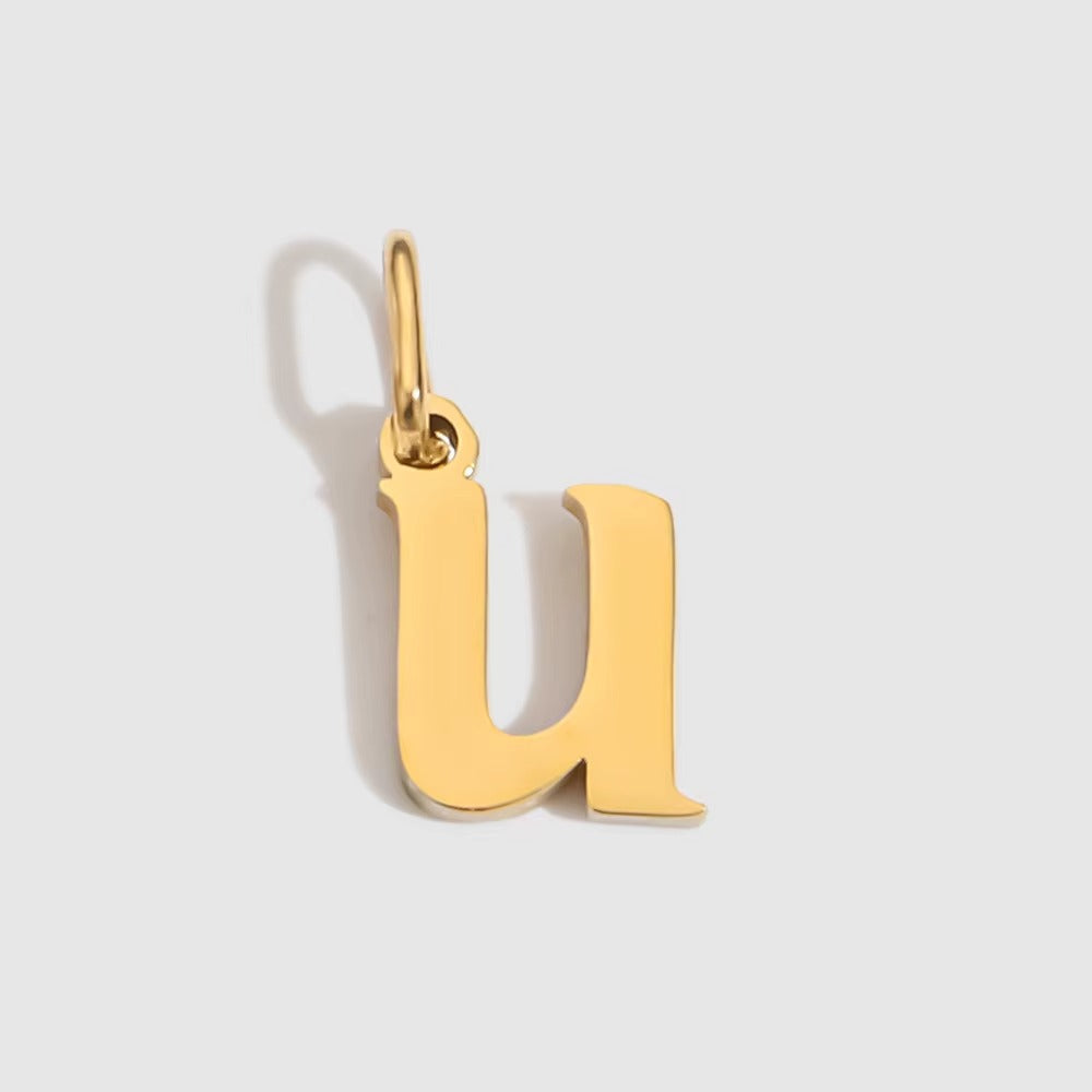 The Letter CHARM in lowercase u, a polished gold pendant in a serif u shape, shown in close-up on a light grey background.