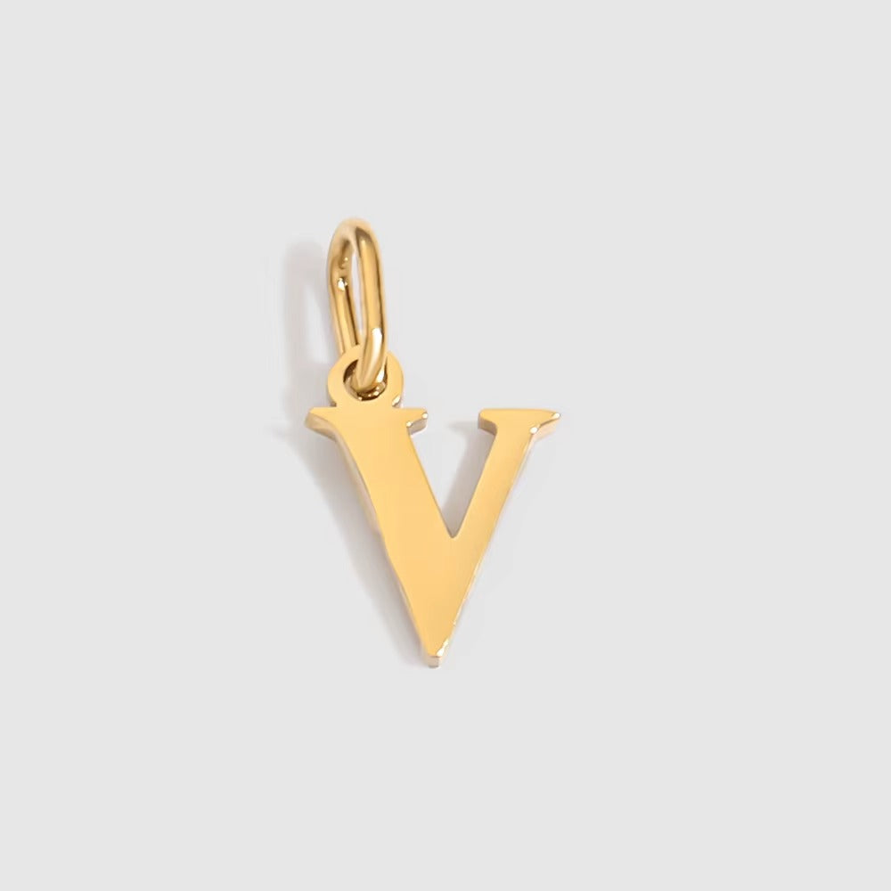 The Letter CHARM in lowercase v, a polished gold pendant in a serif v shape, shown in close-up on a light grey background.