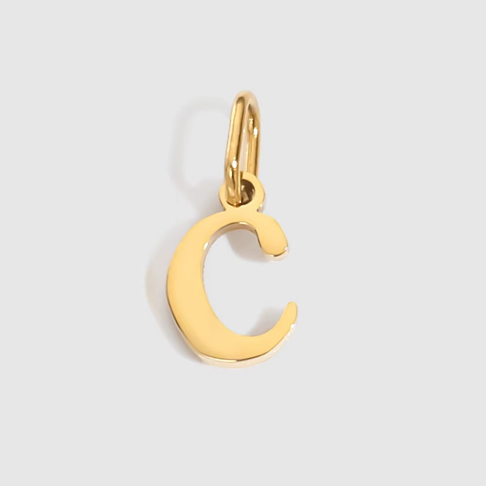 The Letter CHARM in lowercase c, a polished gold pendant in a serif c shape, shown in close-up on a light grey background.