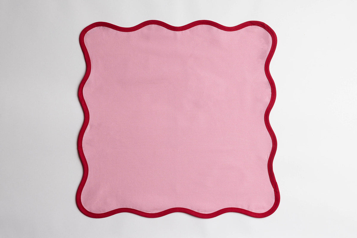 Single pink Lilou Scallop napkin with a wavy red scalloped edge, laid flat and centered on a plain background.