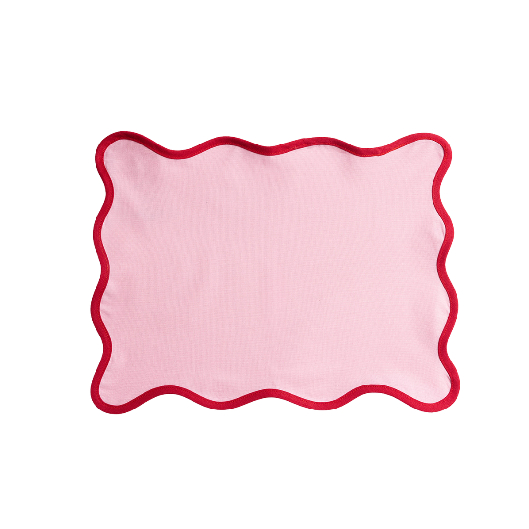 Pink linen Lilou Scallop placemat with a contrasting red wavy scalloped edge, shown flat against a plain white background.