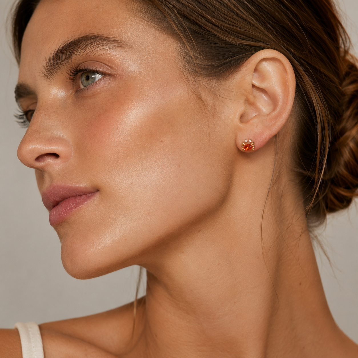 A model wears a gold Little Crab EARRINGS stud with an orange oval cubic zirconia body and gold claw details on her ear.