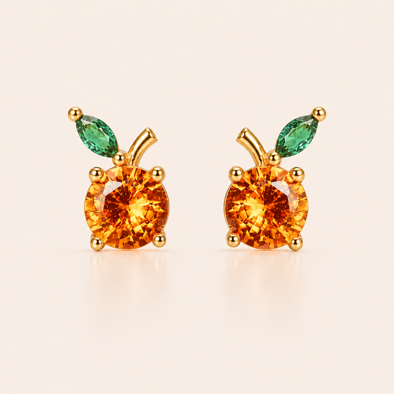 Gold stud earrings from the Little Fruit EARRINGS with a round orange cubic zirconia and a green marquise leaf, evoking a citrus fruit.