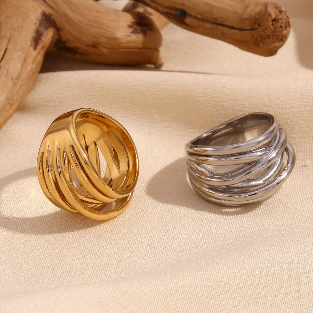 Gold and silver wide wrap-style Lizie RING pieces resting on cream fabric, showing their layered wire band design.