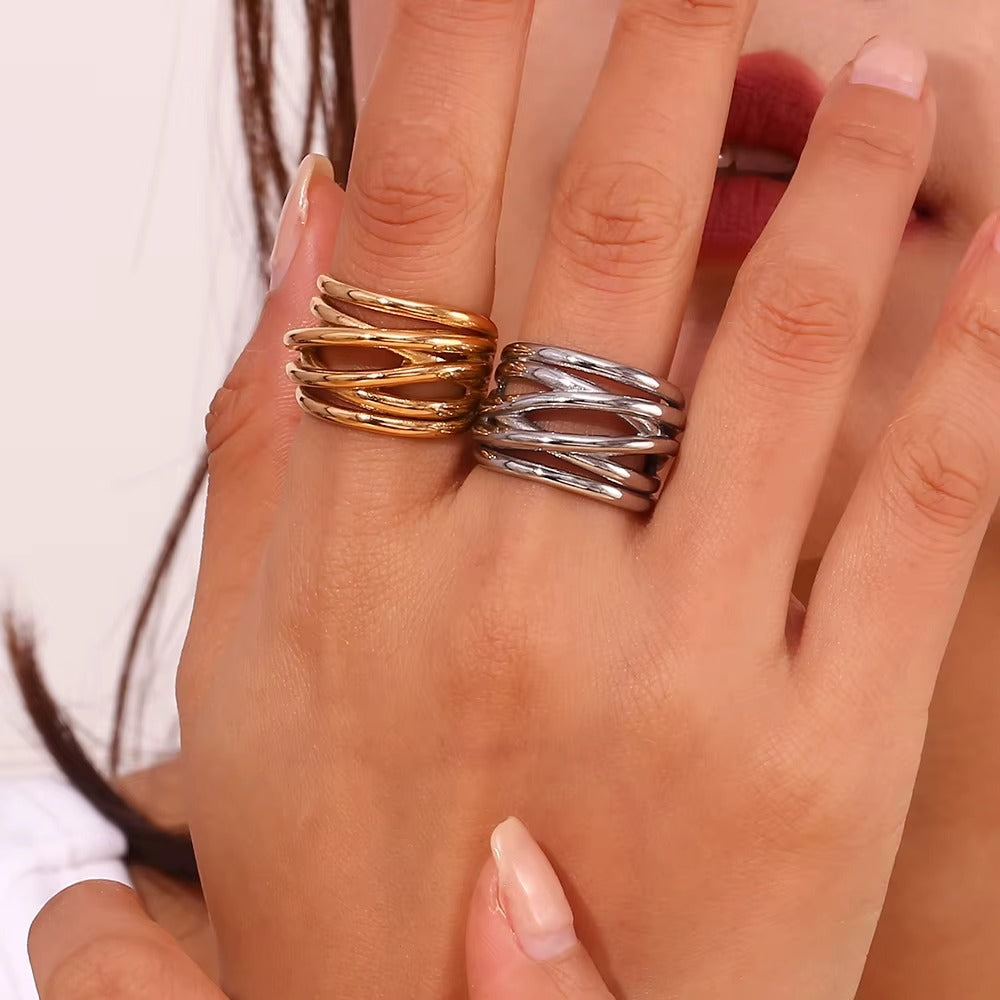 Close-up of a hand stacked with the gold and silver wrap-style Lizie RING pieces worn together on one finger.
