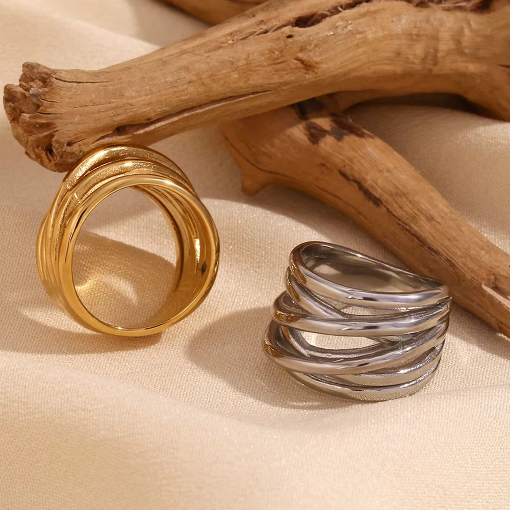 Gold and silver wide wrap-style Lizie RING pieces styled beside driftwood branches on a soft cream fabric.