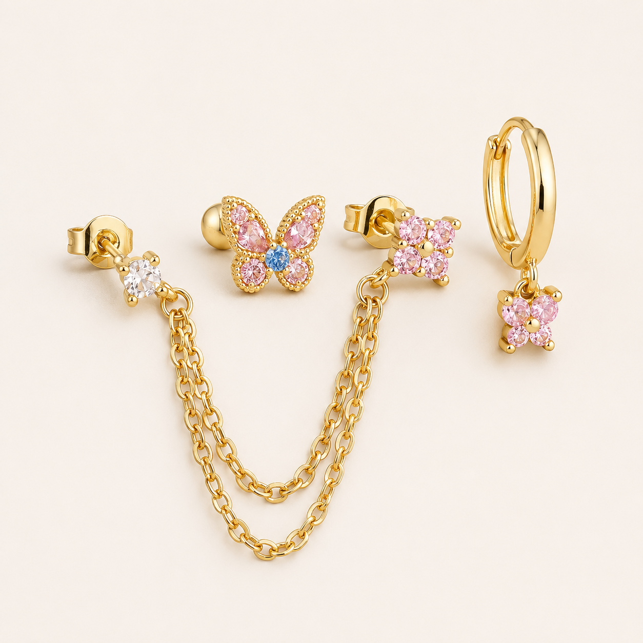 Four-piece Lola SET gold earrings in pink: a chain-drop stud, a butterfly stud, a flower stud, and a hoop with a butterfly charm.