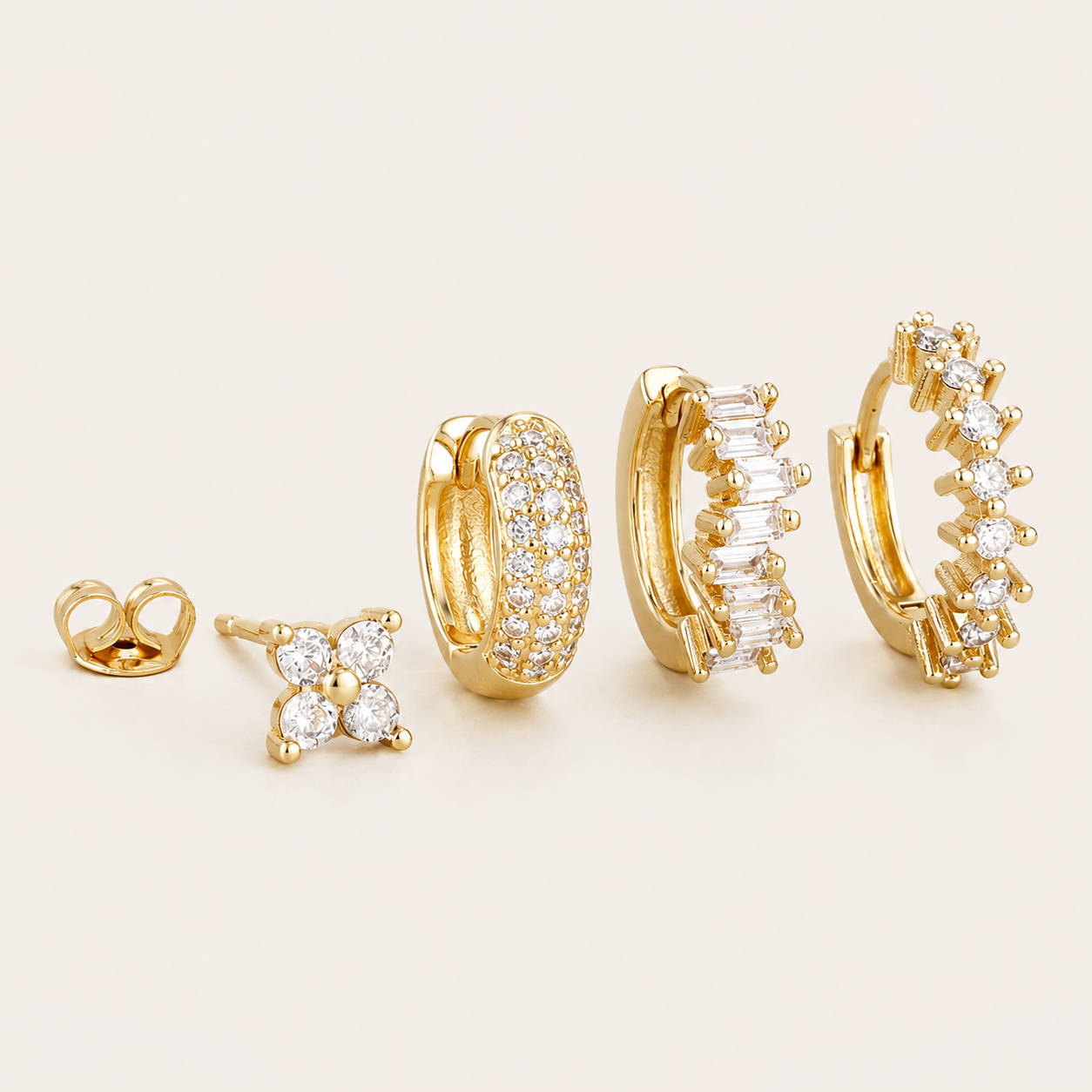 Four-piece Lou SET gold earrings: a four-stone flower stud, a pave hoop, a baguette-stone hoop, and a hoop with round stones.