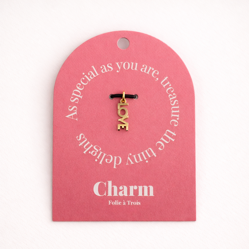 The Love CHARM displayed on a coral pink Charm gift tag, hanging from a black cord against the card's text.