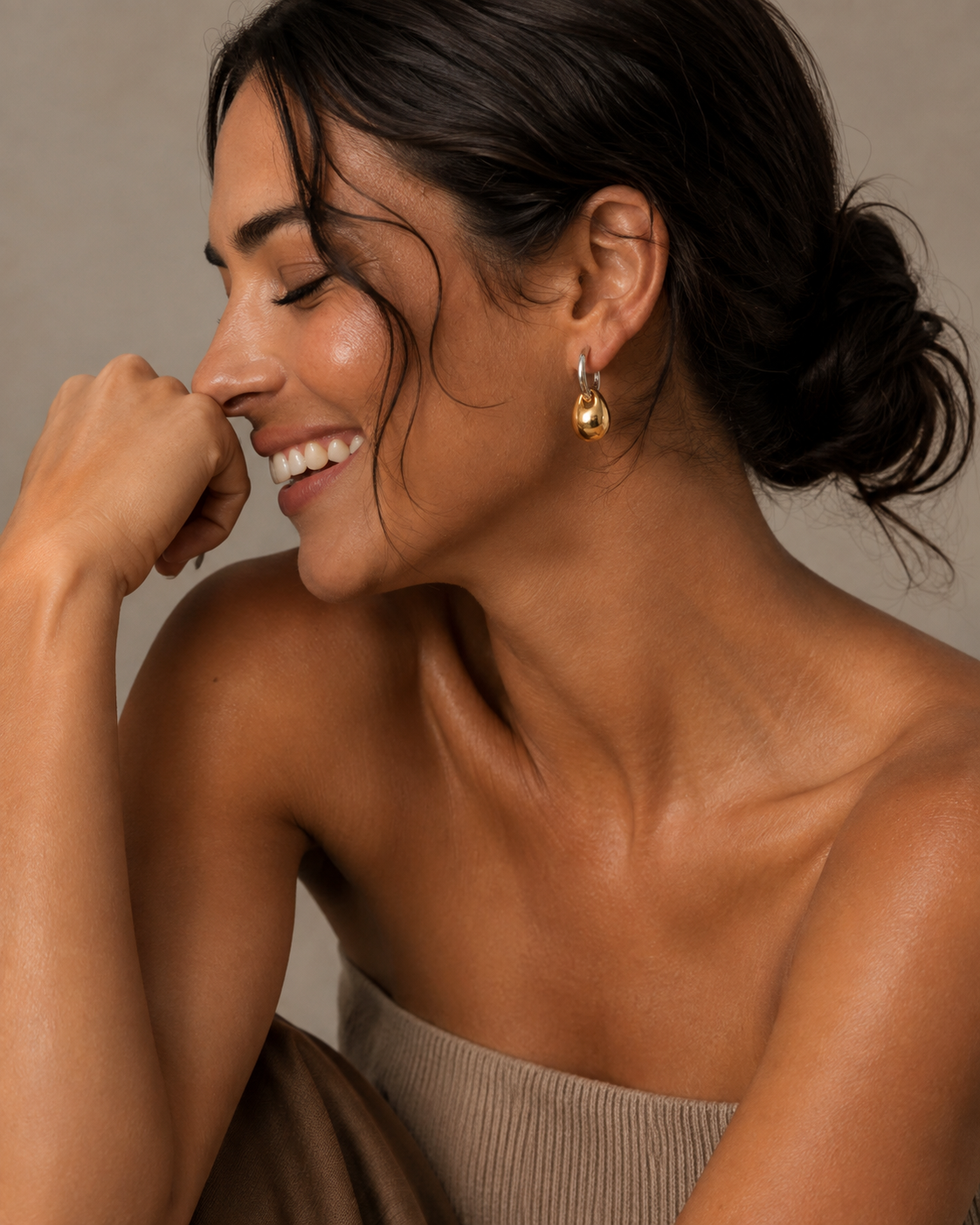 Model wears the gold Folie à Trois Lucent EARRINGS, a glossy pebble-drop hoop earring, in a close-up beauty shot.