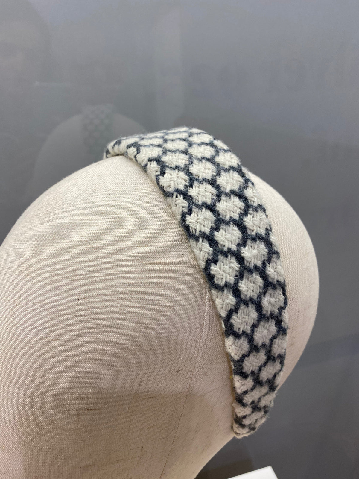 A single navy and cream houndstooth check padded headband on a mannequin head, studio shot.