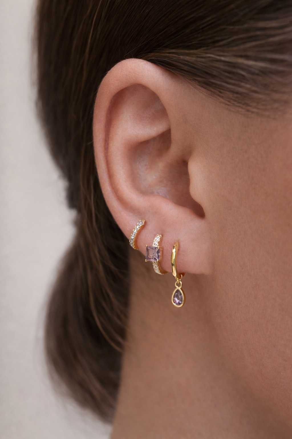 Worn along the ear, Maisie SET layers a pave hoop, a square-stone huggie, and a teardrop dangle in a soft lilac hue.