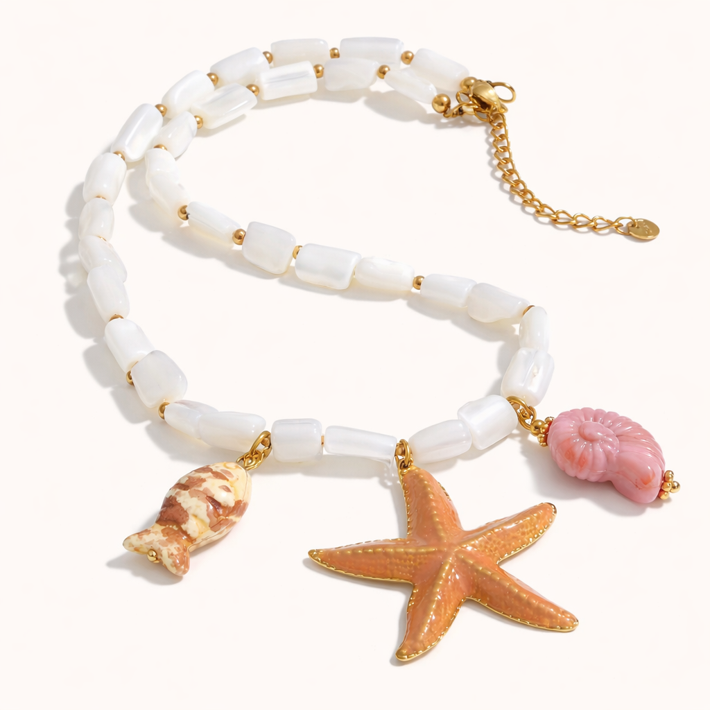 The Malibu NECKLACE laid flat, its mother-of-pearl beads paired with a coral starfish, pink shell, and patterned conch charm.