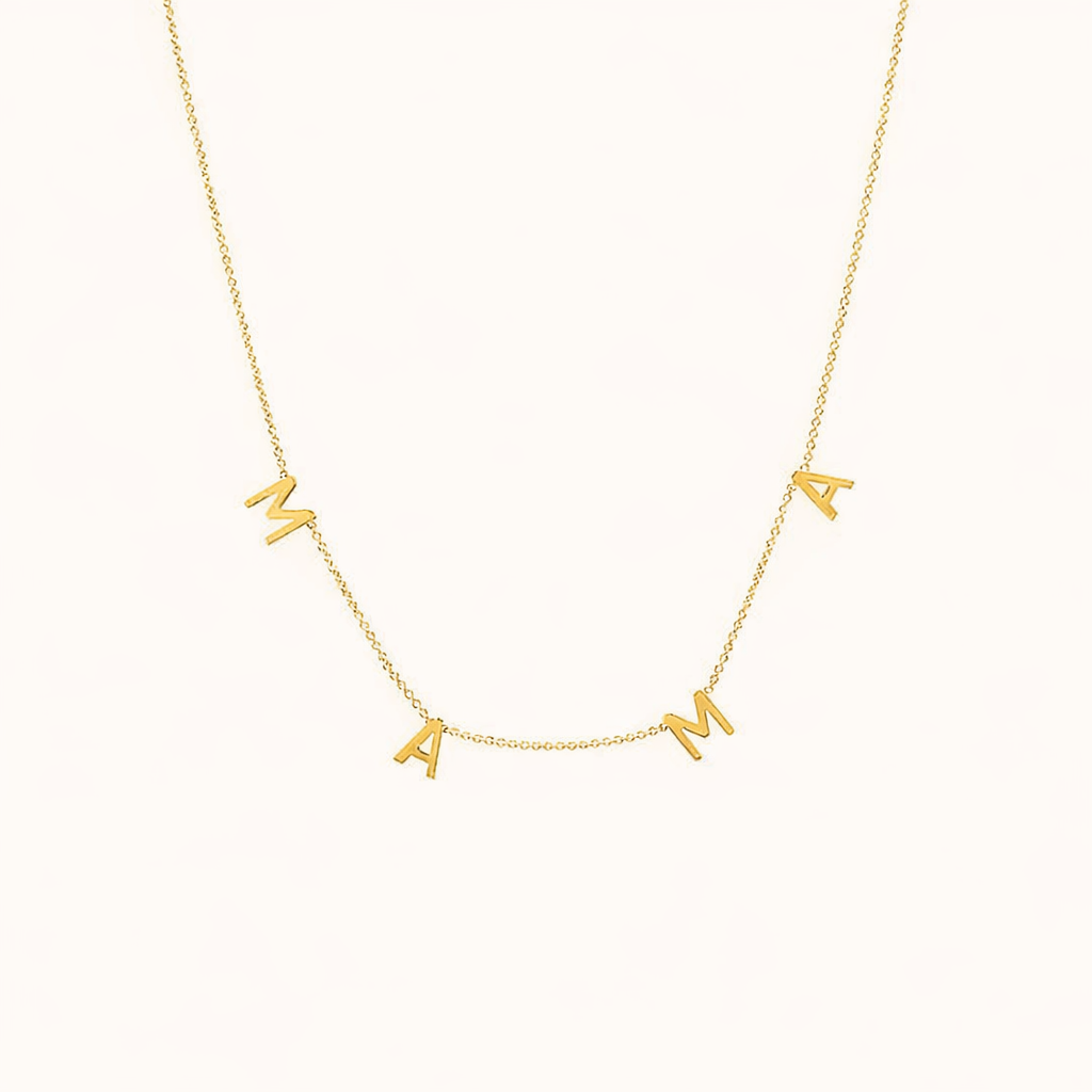 The Mama NECKLACE in gold, individual letters spelling MAMA dangling from a fine chain, shown on a cream background.