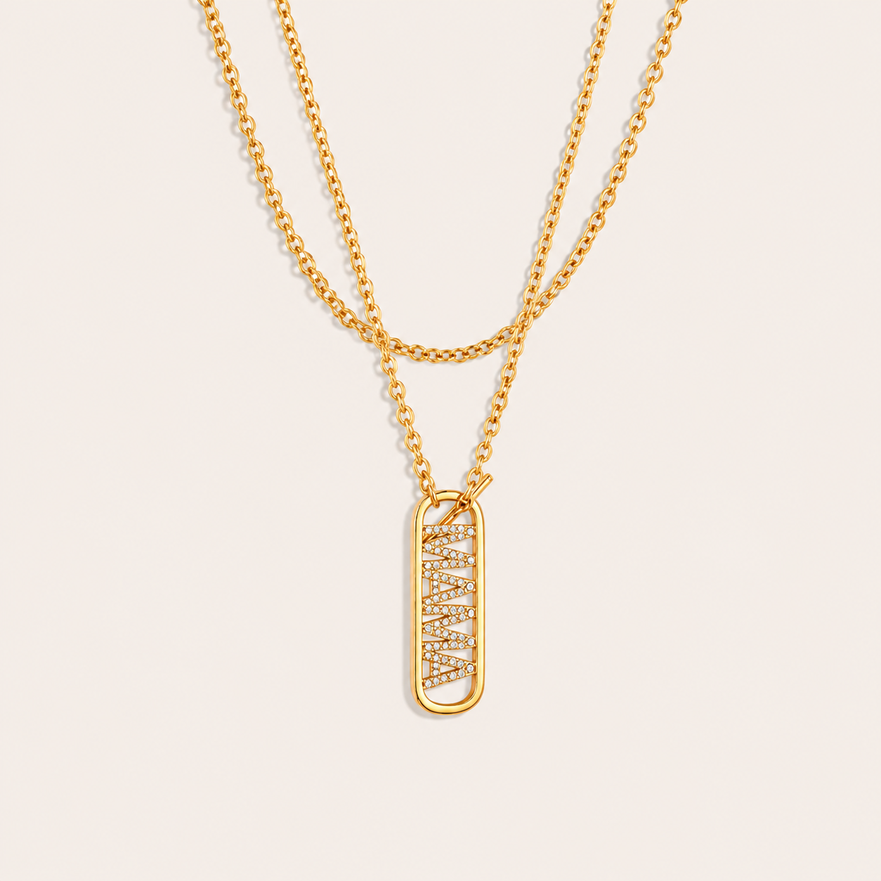 Layered gold chains with a pave mama tag pendant from the Mama Zircon Tag NECKLACE design, laid flat on beige.