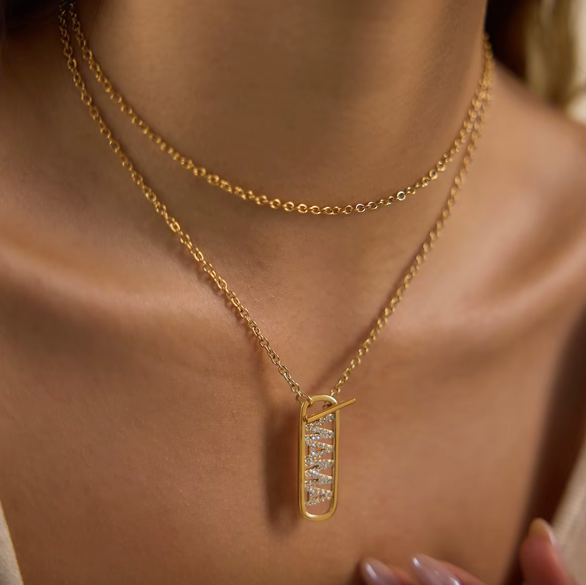 Model wears the layered gold Mama Zircon Tag NECKLACE with its pave tag pendant close to the neckline.