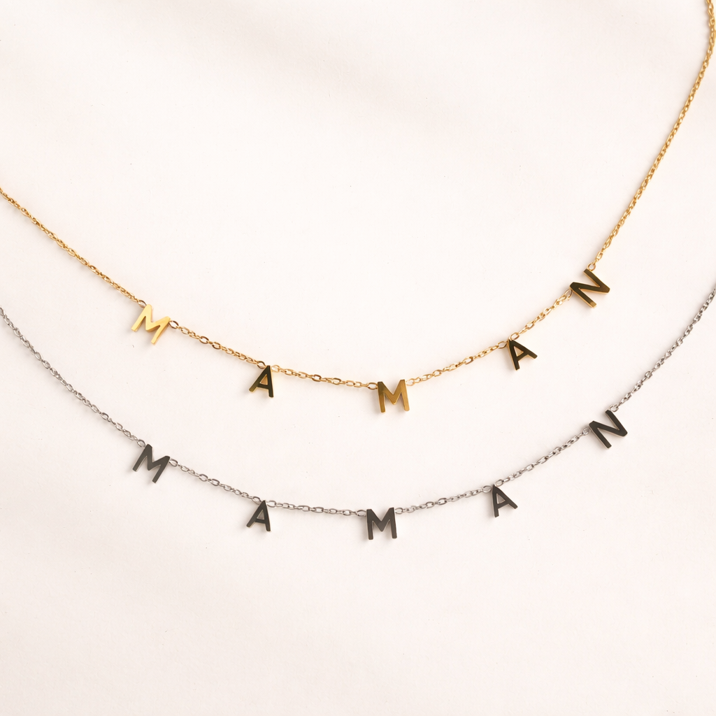 The Maman NECKLACE in gold and silver, a close-up view of the dangling MAMAN letters on two layered fine chains.
