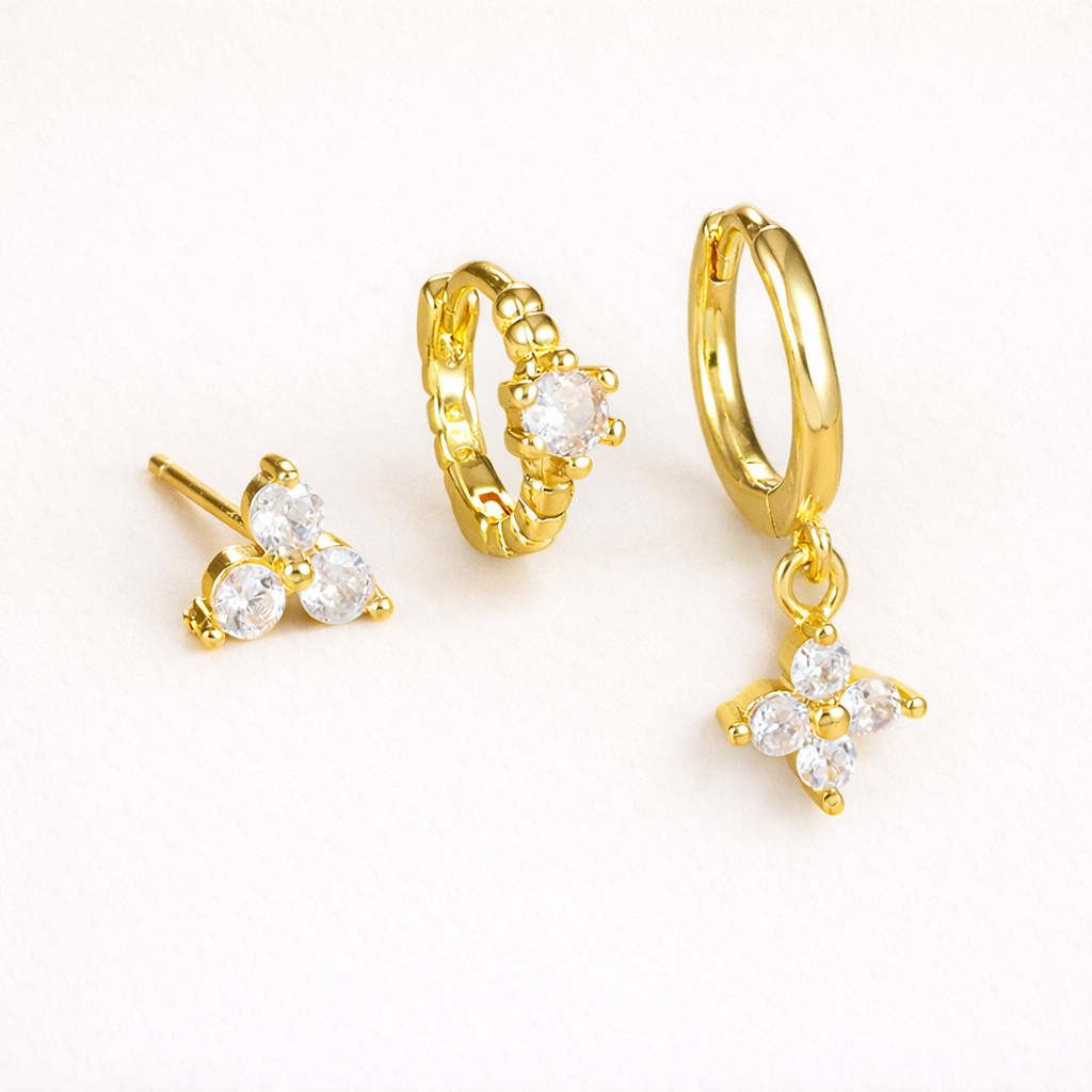 Manon Set of gold jewelry, a trio-stone stud, a beaded pave hoop, and a hoop with a dangling four-point crystal charm.