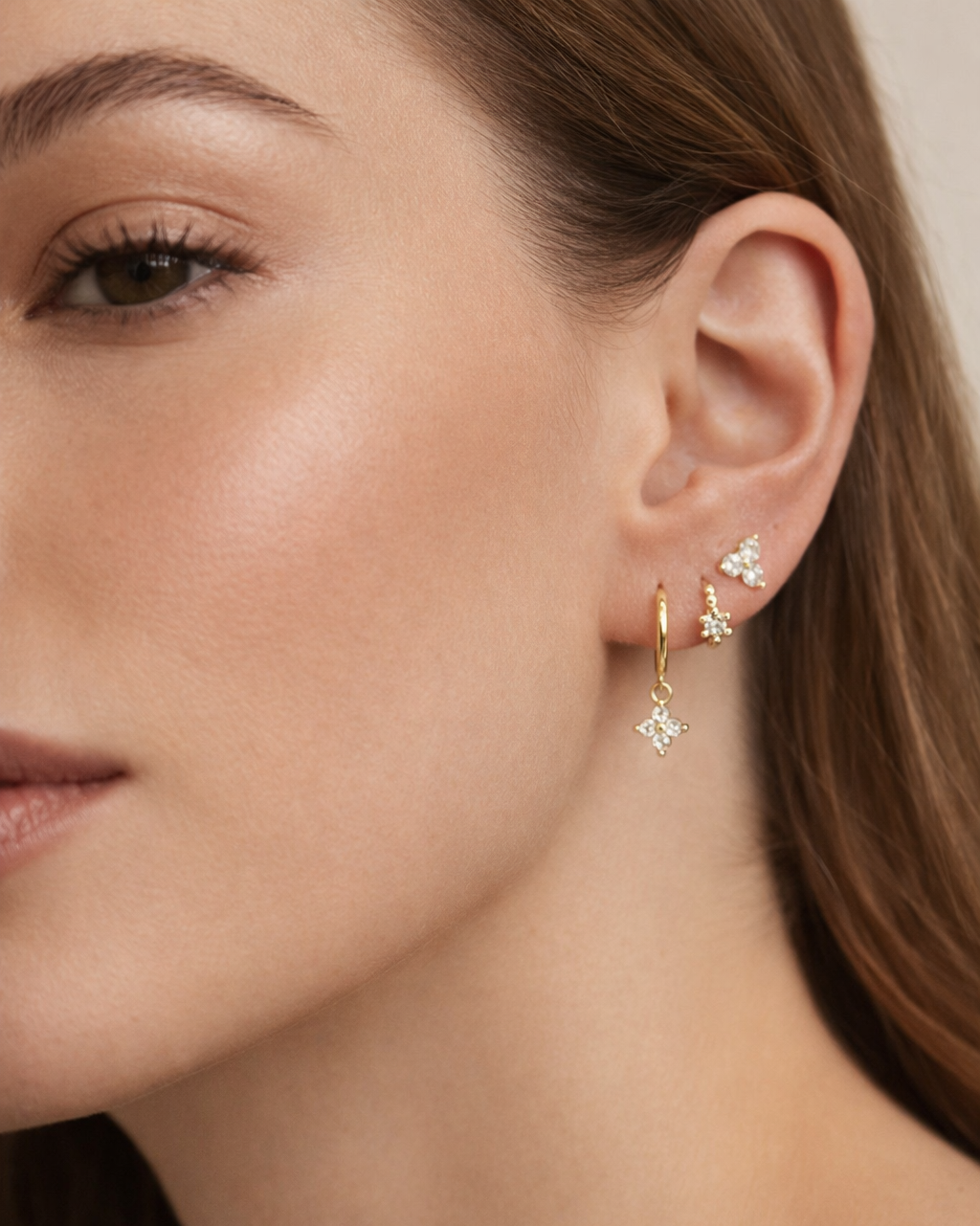 Manon Set worn on the ear in gold, a trio-stone stud, beaded pave hoop, and a hoop with a crystal charm drop.