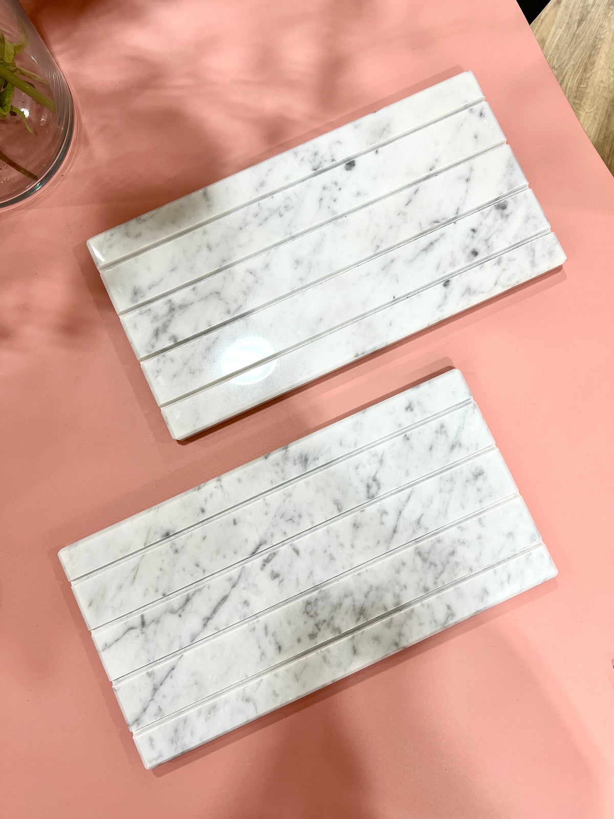 Two Marble Tray DISPLAY slabs in white veined marble with grooved slots for cards, seen from above on a pink table.