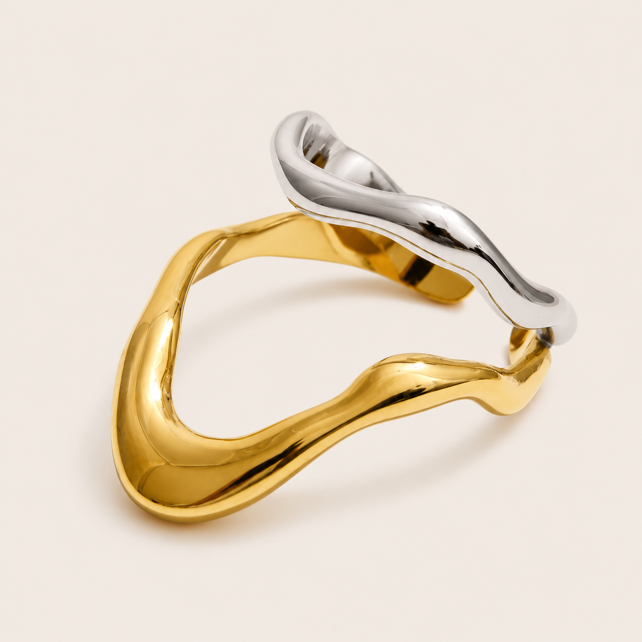 Gold and silver Mare & Soleil RING colorways stacked together, their fluid V-shaped loops overlapping on a cream backdrop.