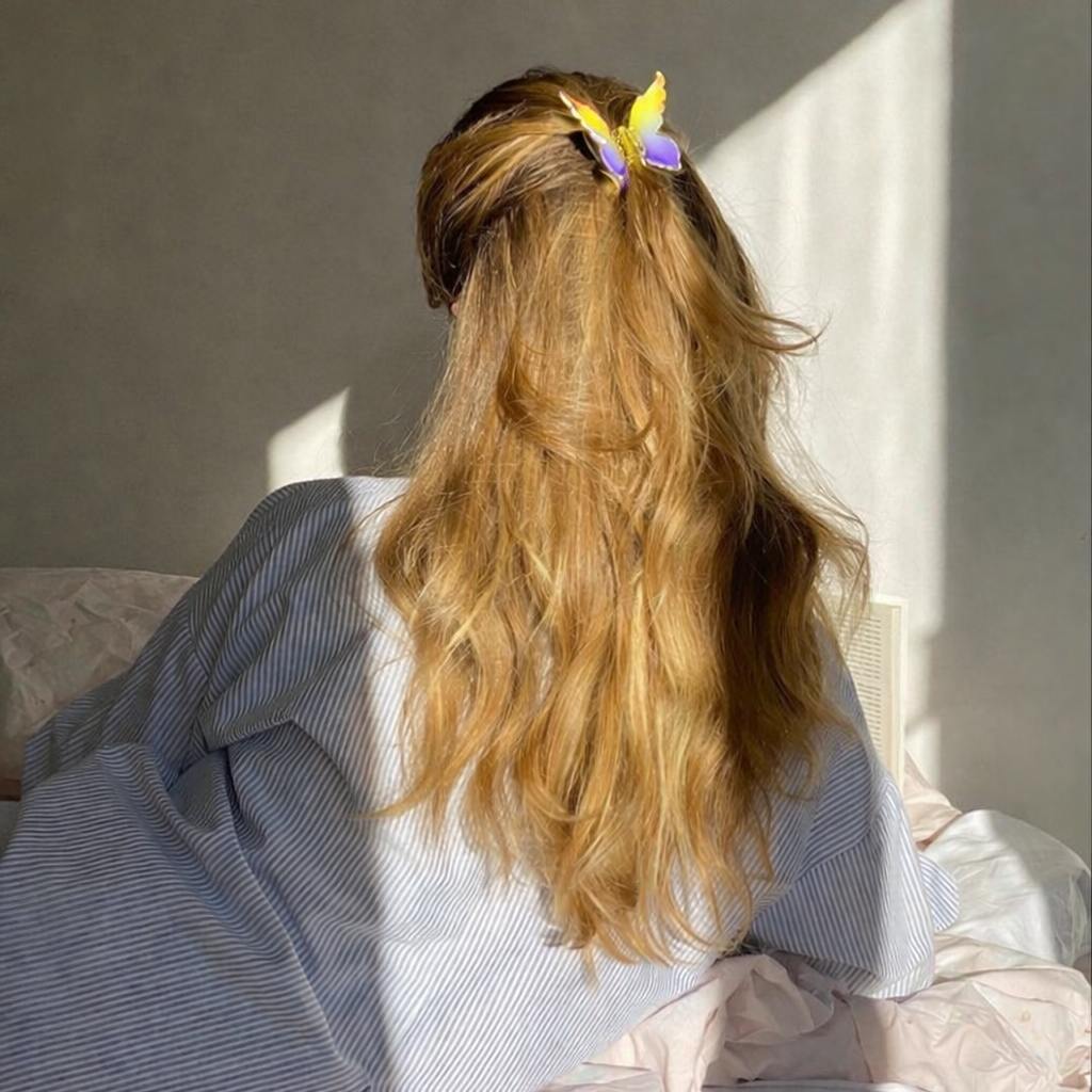 Mariposa HAIR CLIP's yellow and purple butterfly clip worn in blonde hair, photographed in warm sunlight.