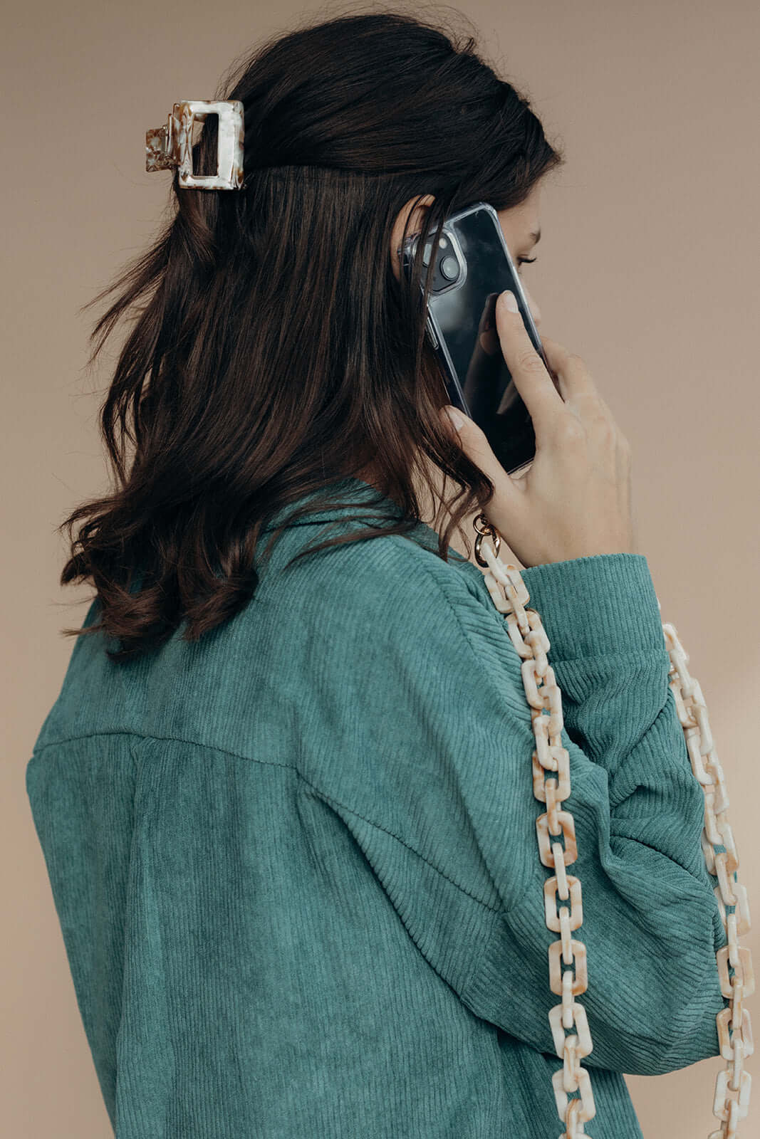 Mathilda HAIR CLIP's white marbled claw clip worn in half-up hair, styled with a teal jacket and chain bag strap.