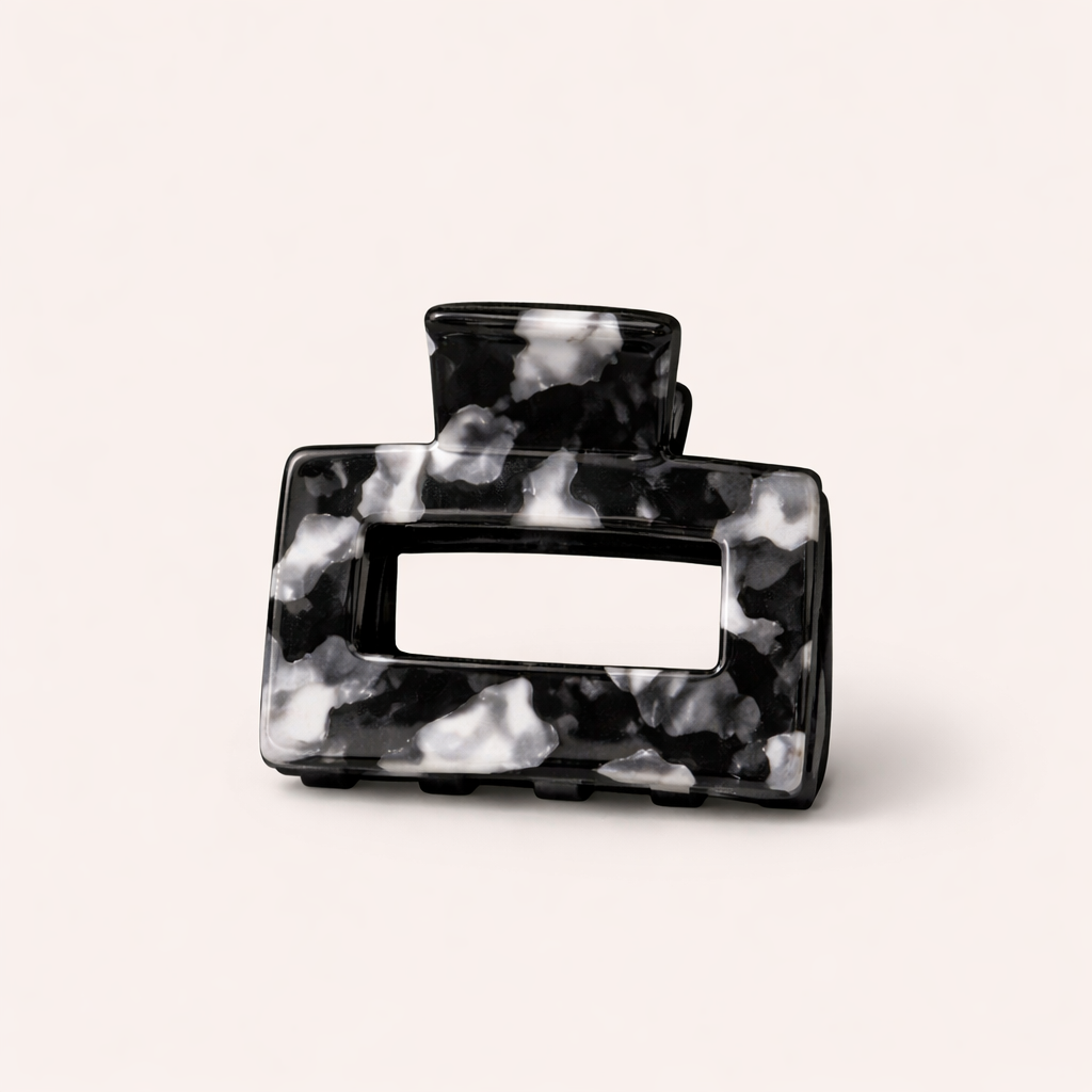 Black and white marbled rectangular acetate claw clip with a cutout handle from the Mathilda HAIR CLIP collection, on a cream studio background.