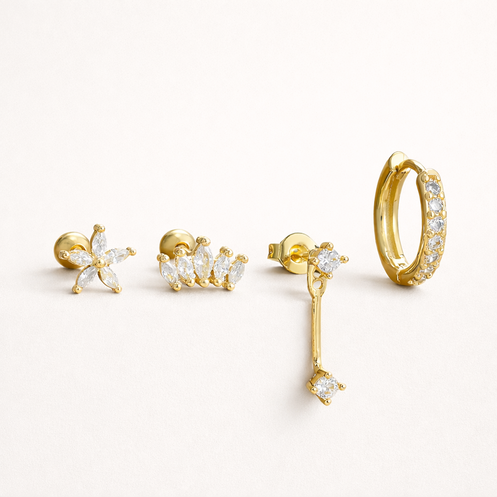 Melanie Set of gold jewelry, a flower stud, a marquise cluster stud, a chain-drop stud, and a pave hoop, laid flat.