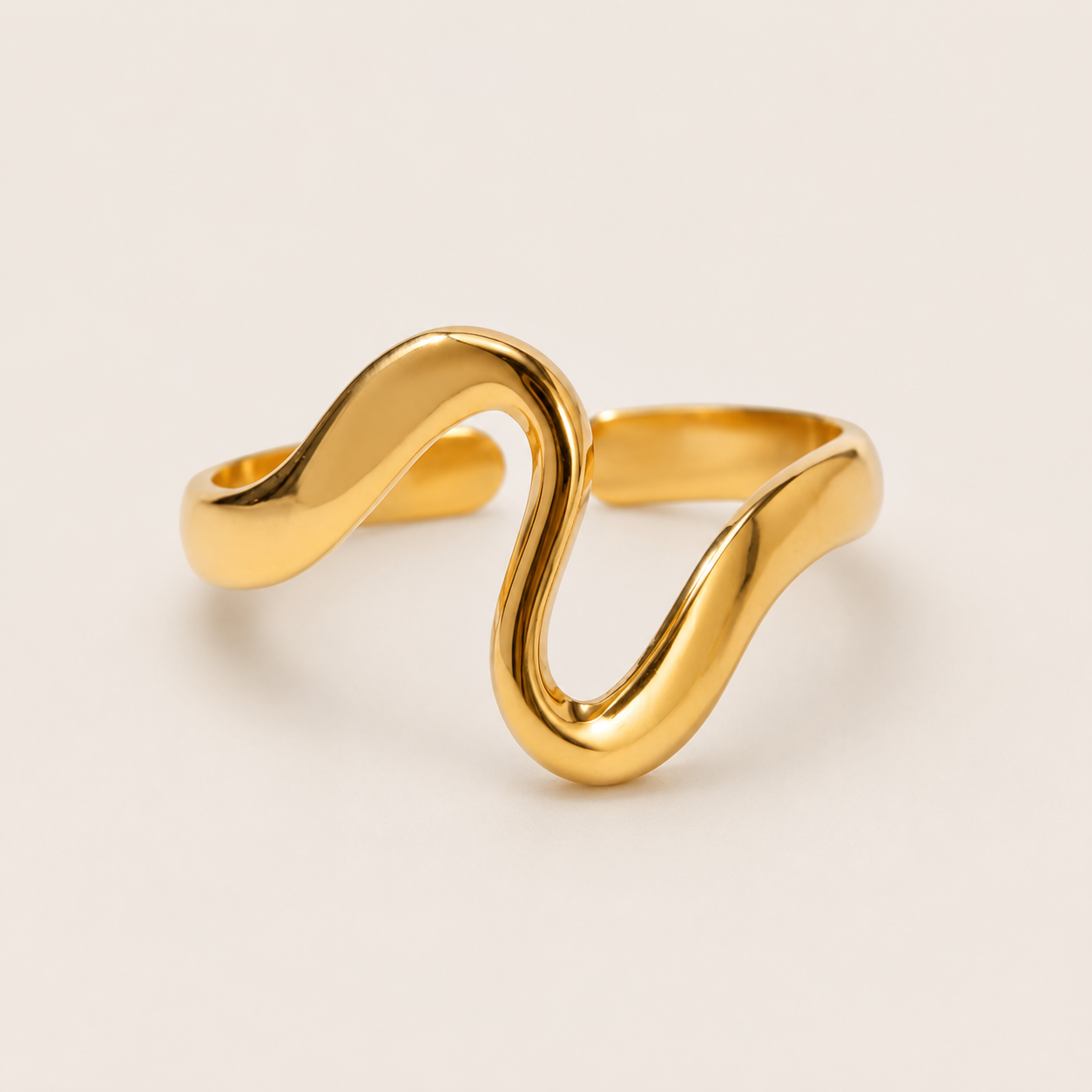 Gold open ring with a fluid S-curve wave design, shown in close-up on a cream backdrop — Folie à Trois Menton RING.