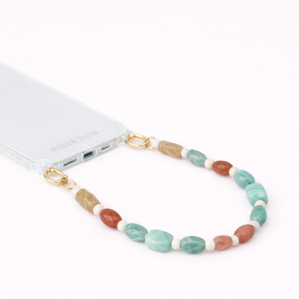 Tan, green, and terracotta beaded Meryn SHORT PHONE STRAP clipped to a clear phone case with gold hardware.