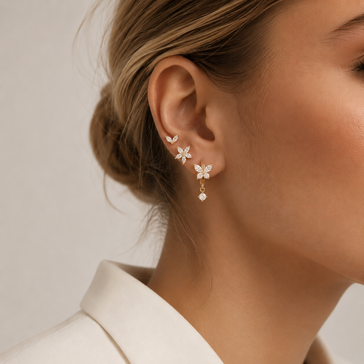 Close-up of a model wearing the three-piece Misha SET gold earrings in clear stones stacked along her ear.