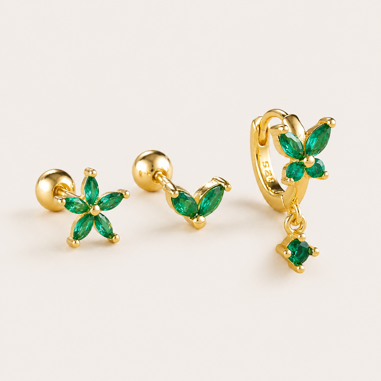 Three-piece Misha SET gold earrings in green: a flower stud, a small V-shaped stud, and a flower hoop with a drop charm.