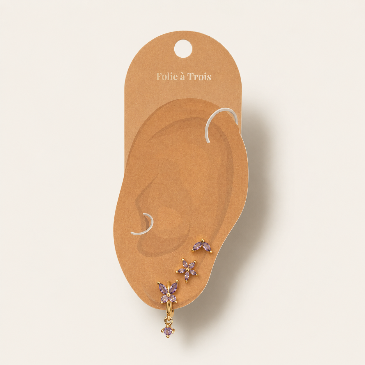 Three-piece Misha SET gold earrings in purple displayed on a Folie a Trois branded ear-shaped packaging card.