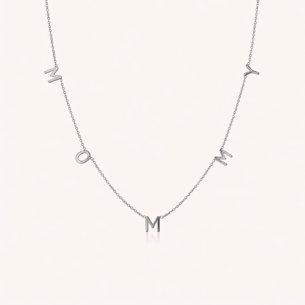 The Mommy NECKLACE in silver, individual letters spelling MOMMY dangling from a fine chain, shown on a cream background.