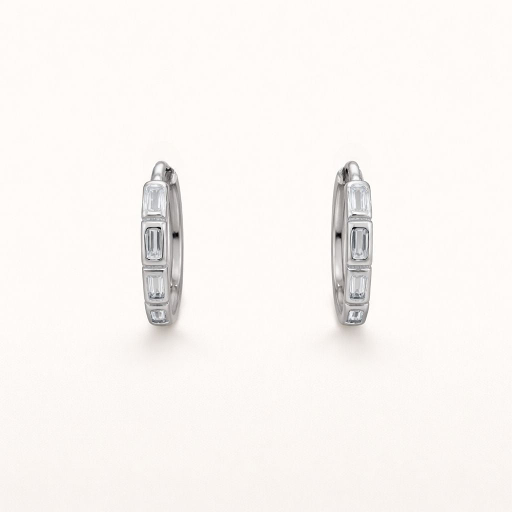 Monday To Friday Earrings set a row of alternating baguette-cut clear stones into a polished silver hoop.