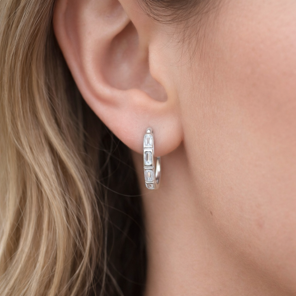 Worn along the ear, Monday To Friday Earrings show their silver hoop lined with sparkling baguette stones.