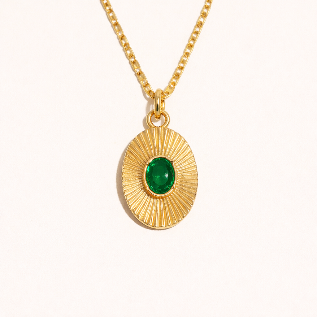 The More Than Friends NECKLACE in gold with a green stone, a sunburst-textured oval pendant on a fine chain, shown flat.