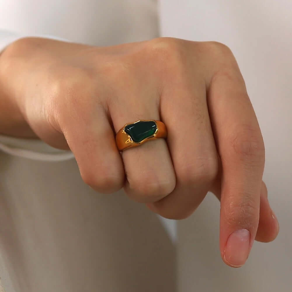 Close-up of a fist wearing the gold signet-style New Fashion RING set with a green cabochon stone.